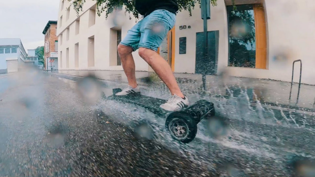 Rider che schizza su una strada bagnata con uno skateboard elettrico ONSRA durante un test sotto la pioggia